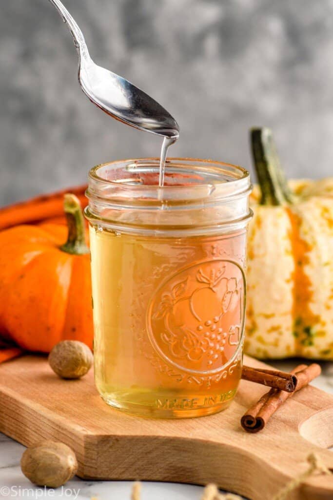 a spoon dripping pumpkin spice syrup into a mason jar full of it