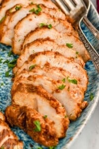 close up of turkey tenderloin recipe sliced and on a platter, garnished with parsley