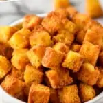 pinterest graphic of a white bowl full of cornbread croutons