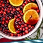 pinterest graphic of overhead of a stock pot full of mulled wine recipe, garnished with fresh cranberries and oranges