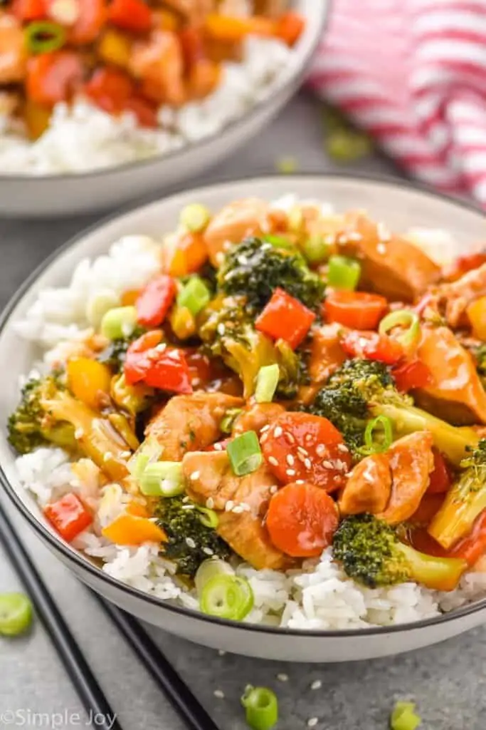 a bowl of rice with chicken and broccoli stir fry on top