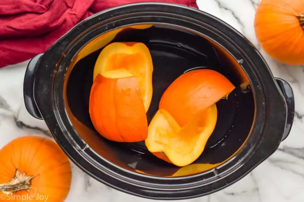 overhead of cut up pumpkin in a crockpot