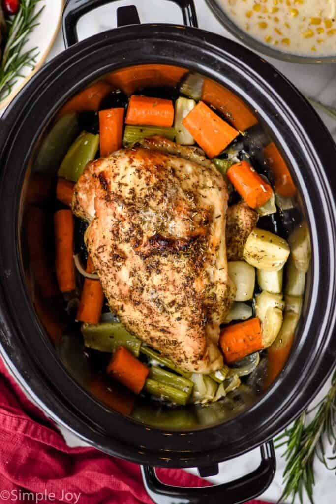 overhead of a turkey breast in a slow cooker on a bed of vegetables