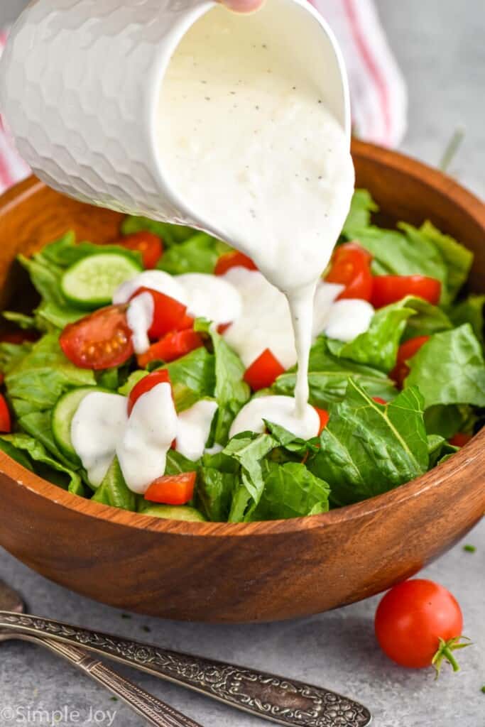 side view of garlic dressing being poured onto a salad