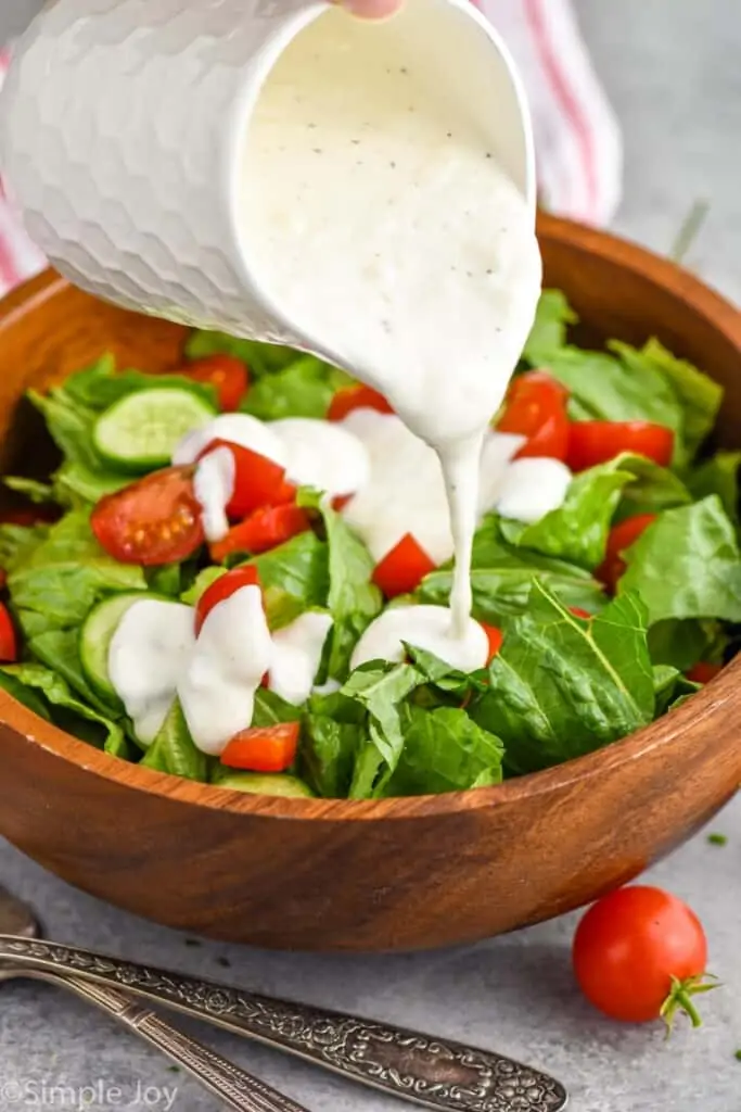 side view of garlic dressing being poured onto a salad