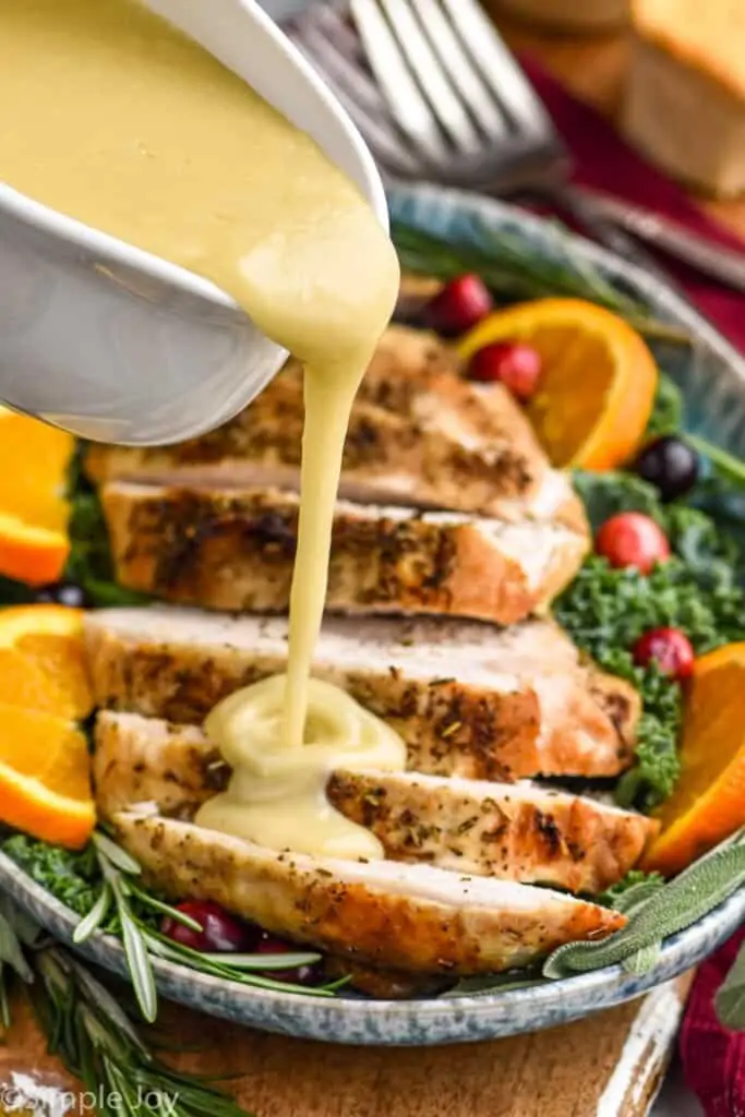 gravy being poured over a cut up slow cooker turkey breast