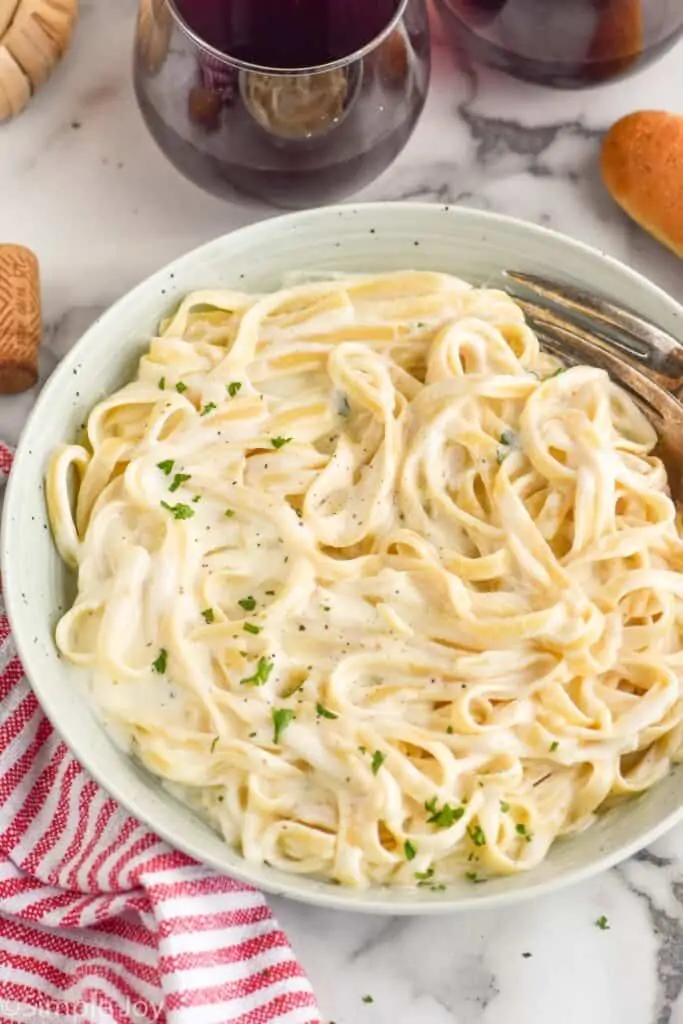 a bowl of fettuccine alfredo garnished with parsley