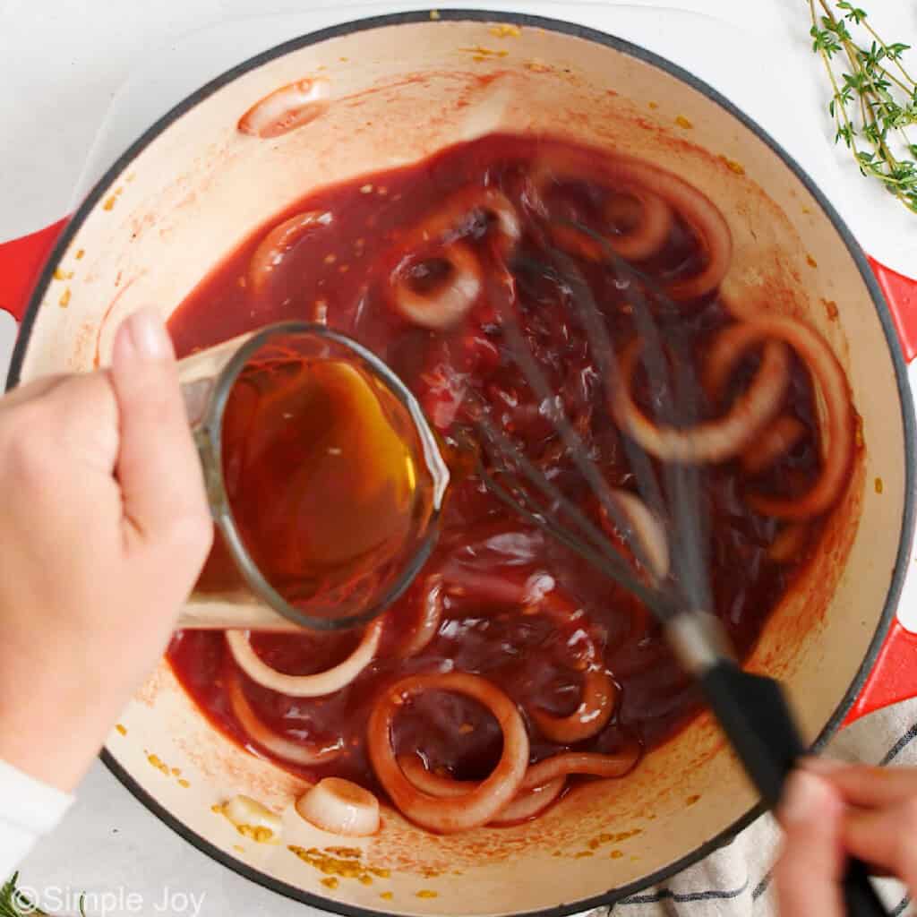 pouring beef broth in a dutch oven
