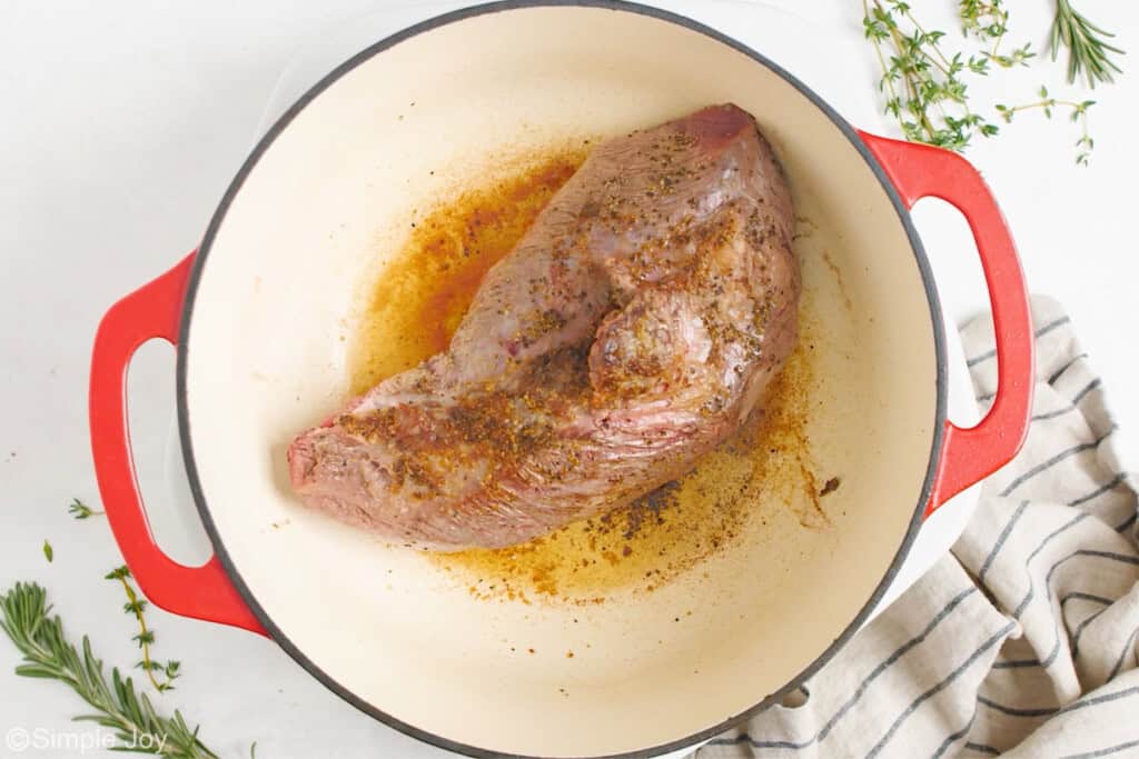 overhead of a pot roast being seared in a dutch oven