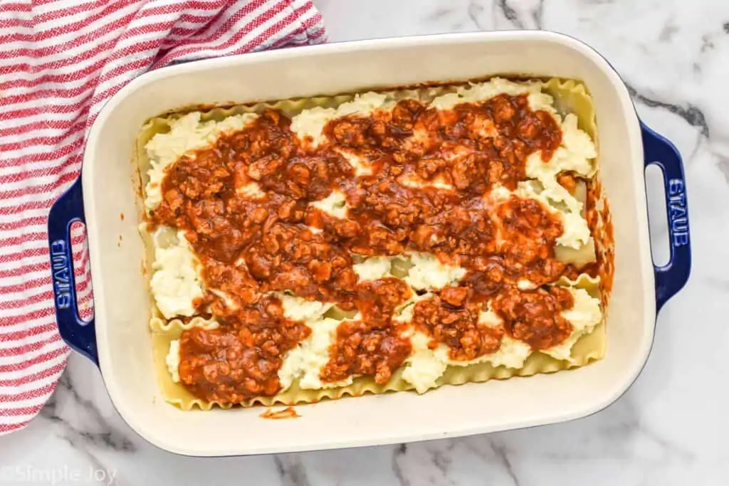 overhead of a lasagna recipe being put together with noodles, cheese, then sauce