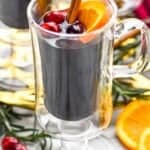 a close up picture of mulled wine in a glass with cranberries and a cinnamon stick and a slice of orange - 10