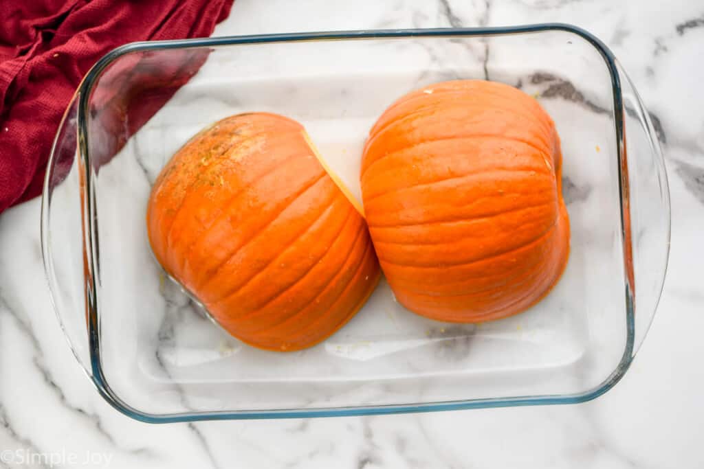 overhead of a small pumpkin has been cut in half and is a baking dish, cut side down