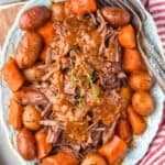 a platter with pot roast, vegetables, and covered with gravy - 11
