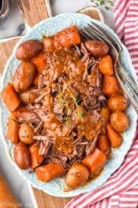 a platter with pot roast, vegetables, and covered with gravy