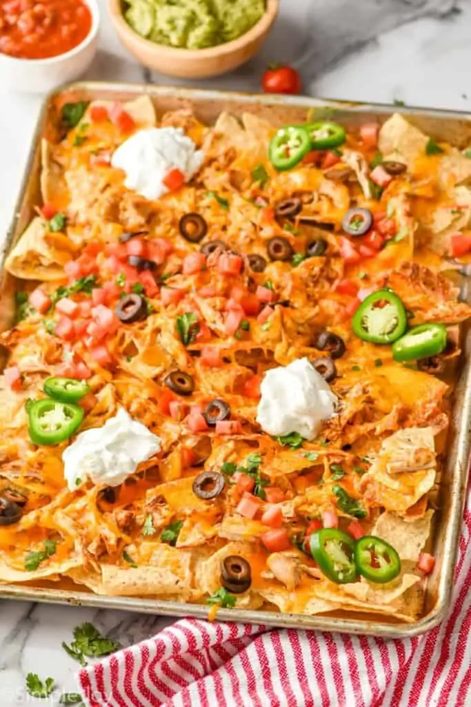 side view of a sheet pan full of shredded chicken nachos