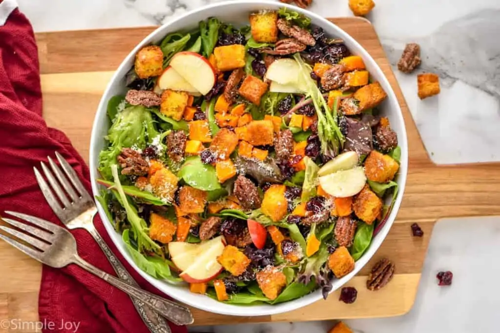 overhead of a fall salad in a white bowl on a cutting board