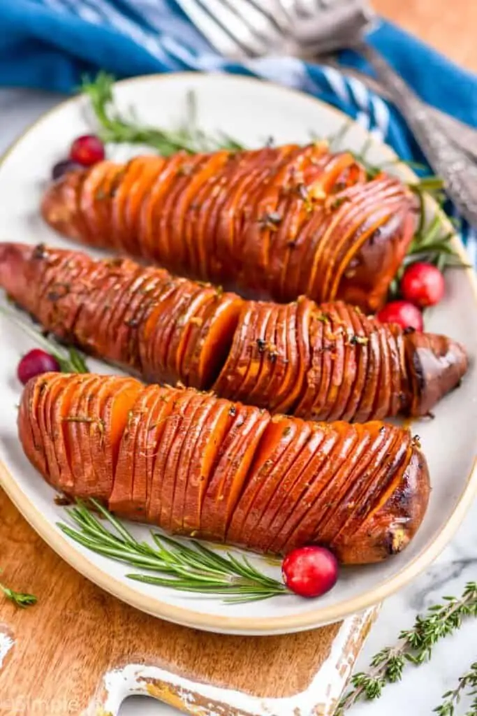 side view of three sweet potatoes cooked hasselback style on a platter