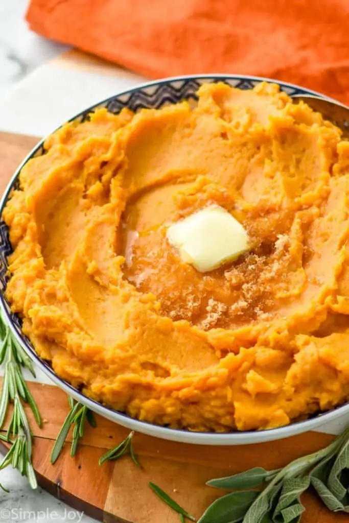 side view of a bowl of mashed sweet potatoes with melting butter and brown sugar