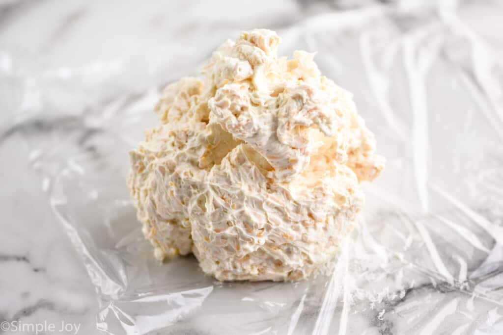 a ball of cream cheese mixture on a sheet of plastic wrap