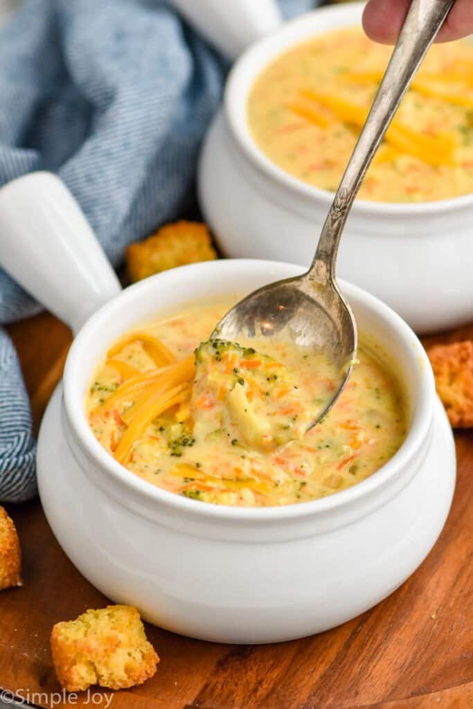 a spoon dipping into a bowl of instant pot broccoli cheddar soup
