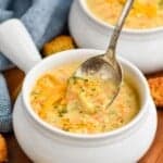 a spoon dipping into a bowl of instant pot broccoli cheddar soup