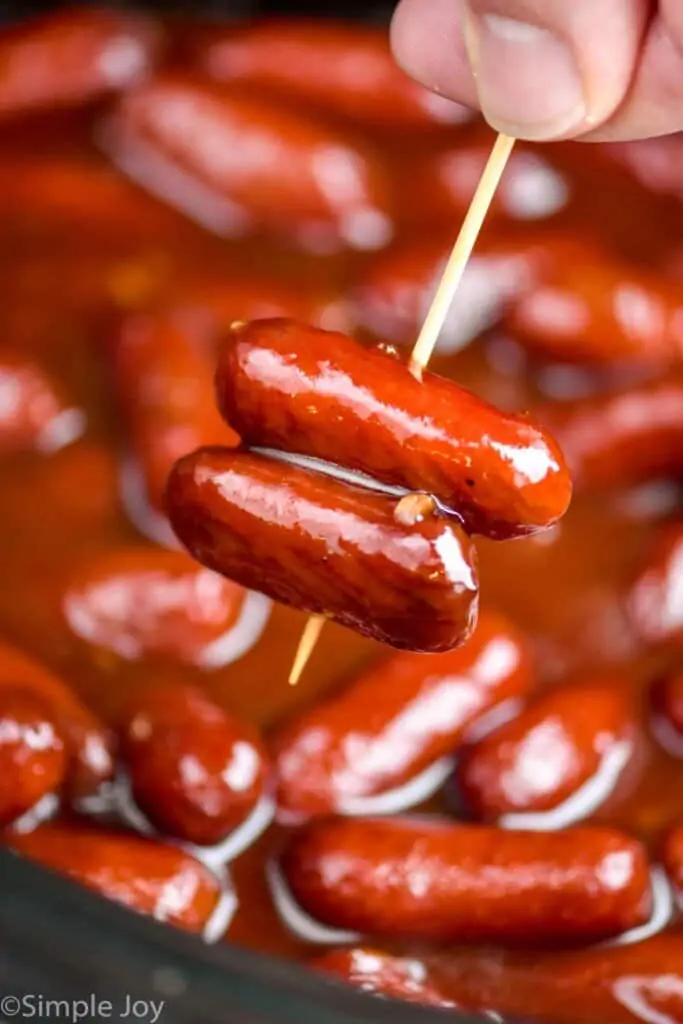 two cocktail wieners covered in BBQ sauce and pierced with a toothpick