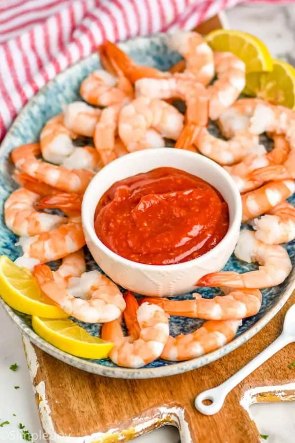 small white bowl with shrimp cocktail sauce on a platter with shrimp