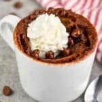 a small white mug with a chocolate mug cake in it, topped with whipped cream - 8