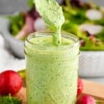 side view of a jar green goddess dressing with a spoon coming out - 6