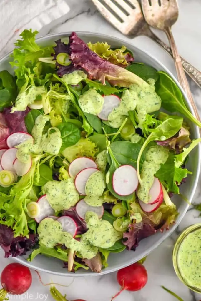 overhead view of green goddess salad dressing over a fresh greens in a salad bowl