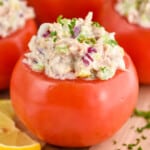 side view of tuna stuffed tomato recipe on a wood cutting board - 10