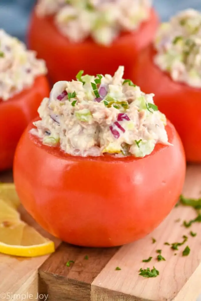 side view of tuna stuffed tomato recipe on a wood cutting board