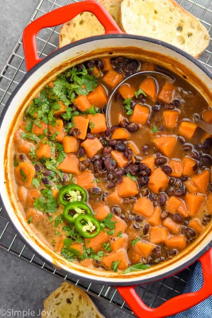 overhead view of a stock pot full of vegan black bean soup, garnished with fresh jalapeno slices and freshly minced cilantro