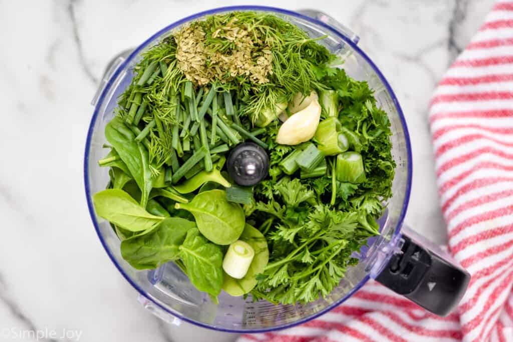 overhead view of fresh green herbs in a food processor