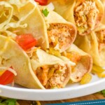 pinterest graphic of close up of a plate of taquitos topped with lettuce, tomatoes, and cheese