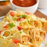 Pinterest graphic of a plate of chicken taquitos topped with lettuce, tomatoes, and shredded cheese