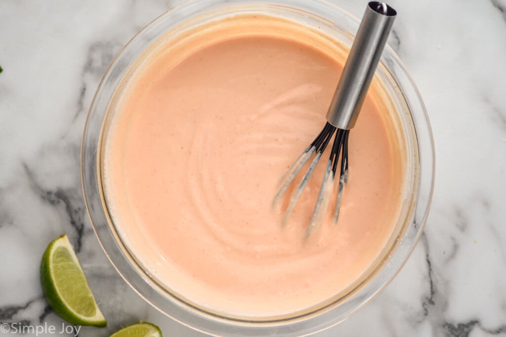 overhead of a bowl of fish taco sauce recipe with a whisk in it