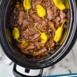 pinterest graphic of overhead of a Mississippi pot roast in a crock pot after being cooked and shredded