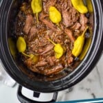 pinterest graphic of overhead of a Mississippi pot roast in a crock pot after being cooked and shredded