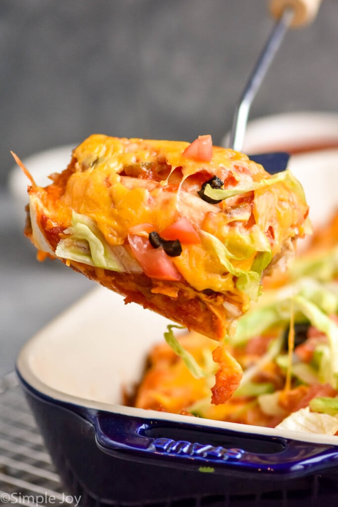 baked burritos being dish up from a casserole dish