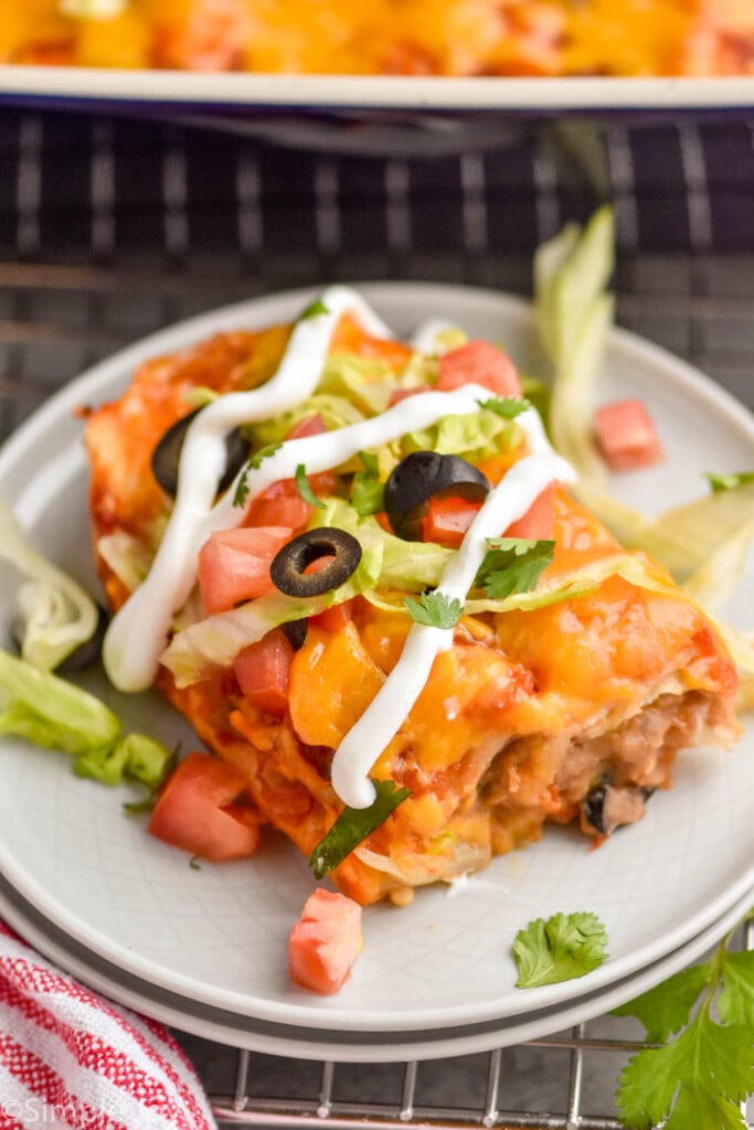 baked burritos on a plate with toppings and sour cream