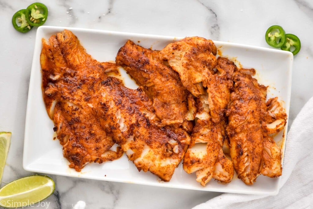 overhead of seasoned cooked cod for fish tacos on a platter