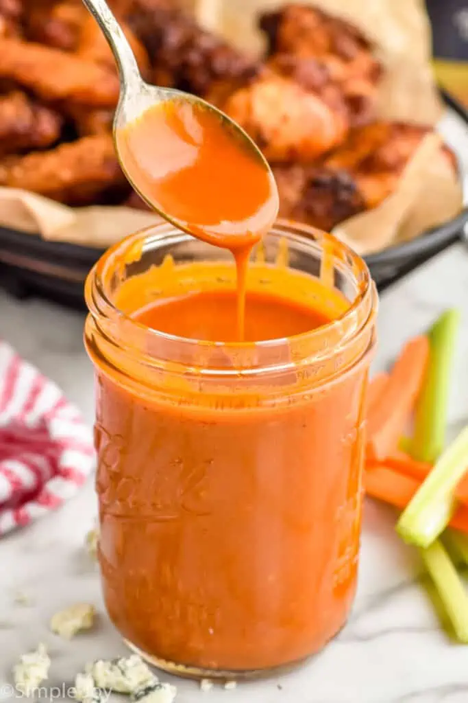 spoon dripping buffalo sauce into a mason jar full of it