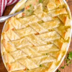 a spoon digging in to a chicken pot pie casserole recipe that has a puff pastry lattice top
