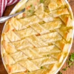 a spoon digging in to a chicken pot pie casserole recipe that has a puff pastry lattice top - 25