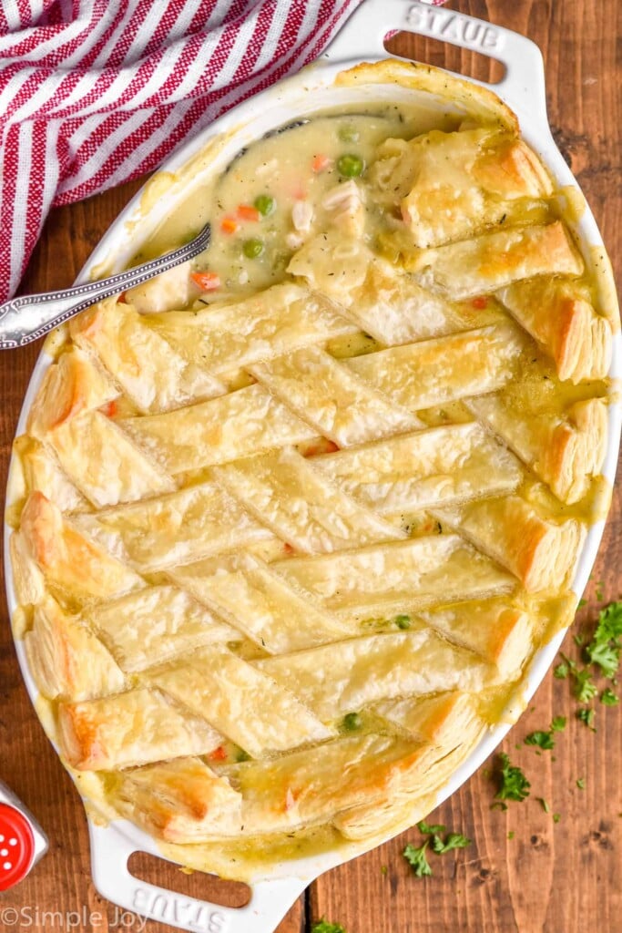 a spoon digging in to a chicken pot pie casserole recipe that has a puff pastry lattice top