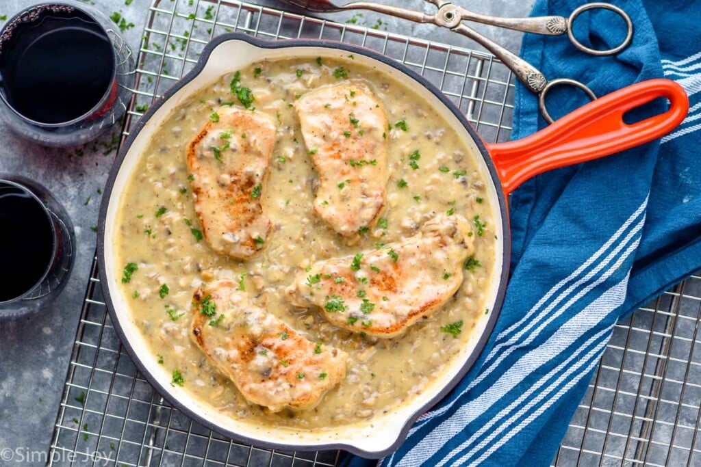 overhead of a pan with a cream sauce and four pork chops