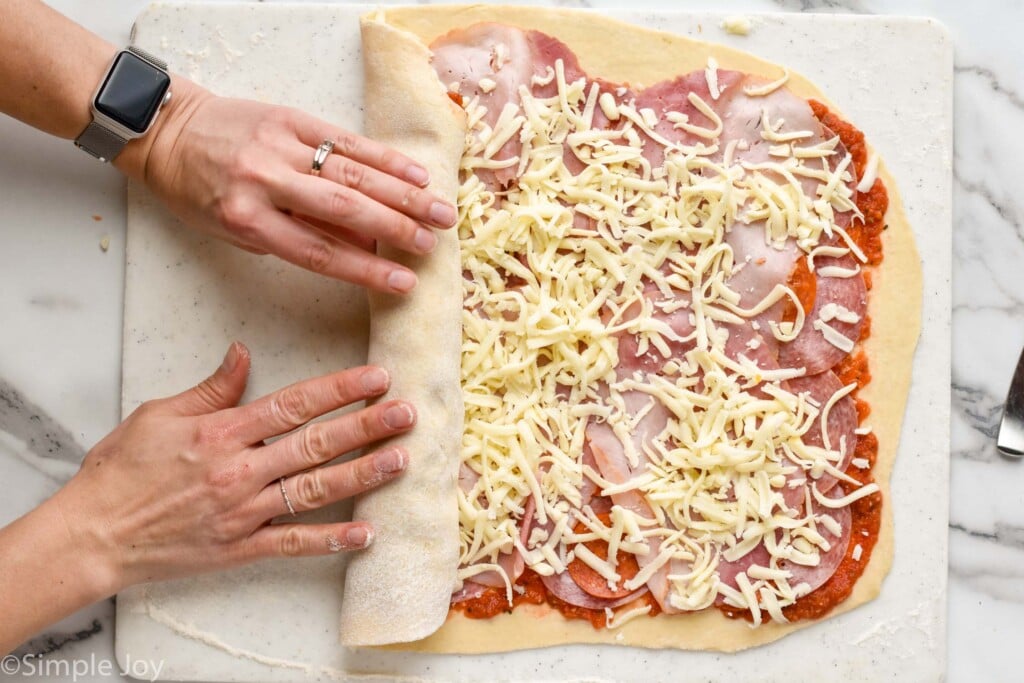 hands rolling up a stromboli