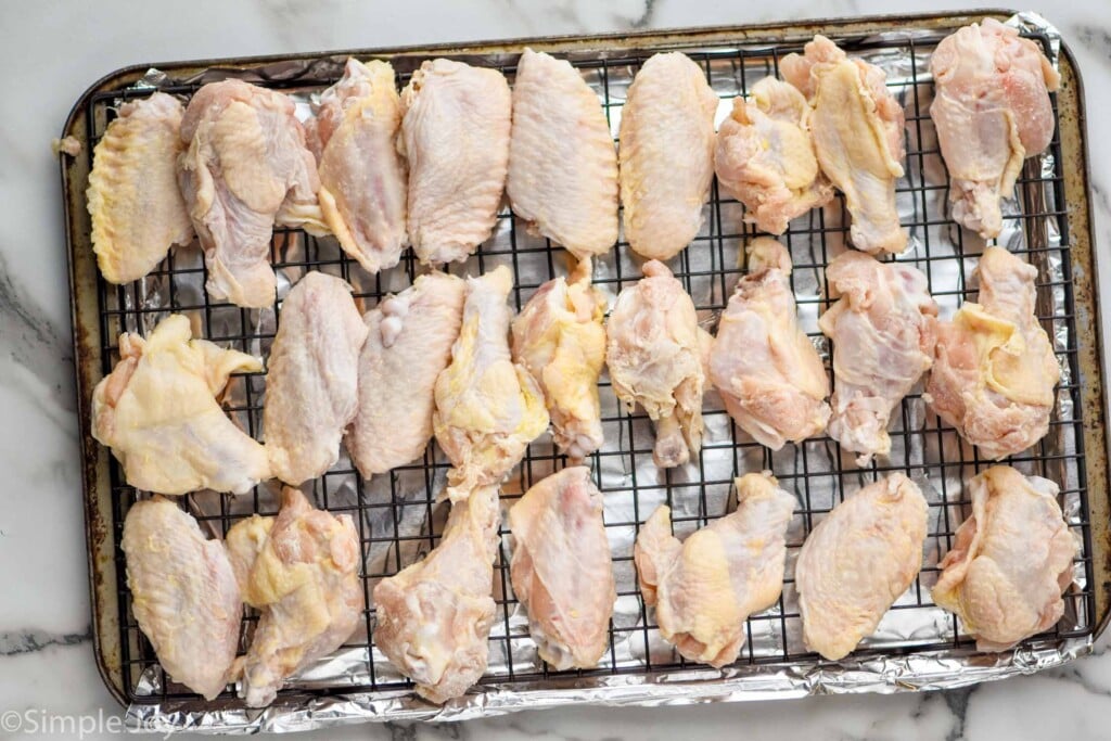 chicken wings on a wire rack that has been fitted in a rimmed baking sheet lined with aluminum foil