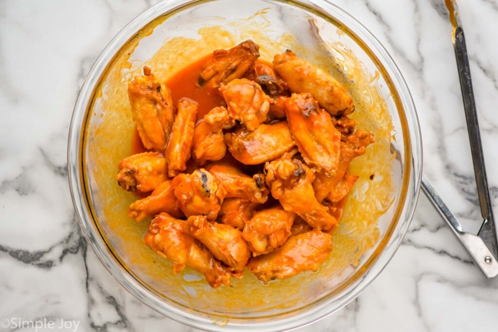baked chicken wing recipe in a big bowl coated in buffalo sauce